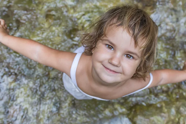 Schattige lachende peuter kind meisje op waterval achtergrond — Stockfoto