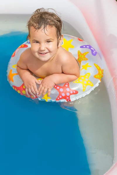 Young happy child girl swimming in pool with swimming ring — Stock Photo, Image