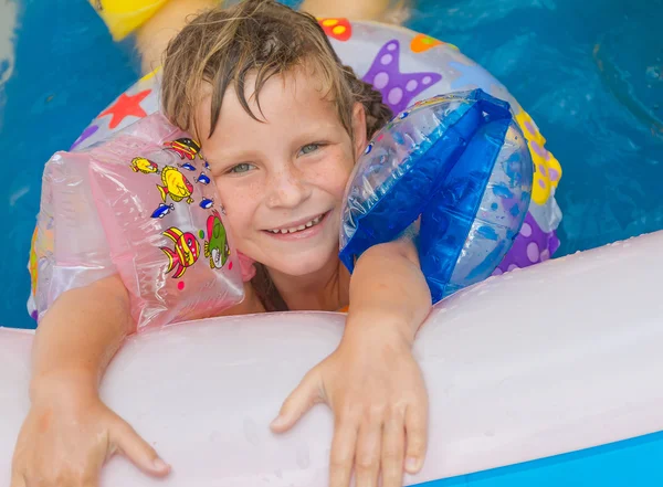 Молода щаслива дівчинка, що плаває в басейні з плавальним кільцем — стокове фото