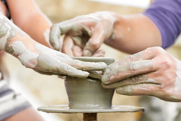 Niño aprendiendo a hacer una olla en una rueda de cerámica, viejo alfarero h — Foto de Stock