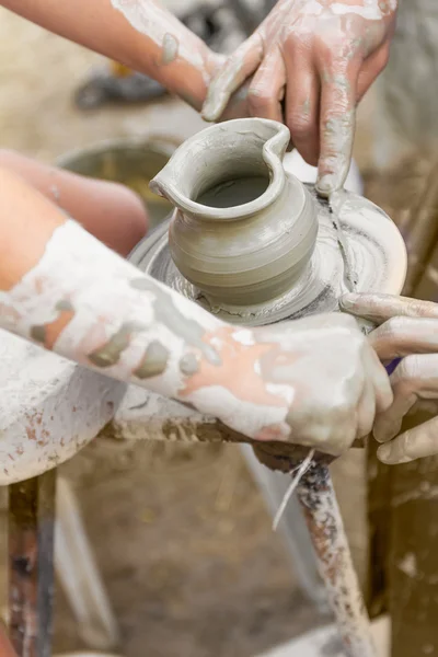 Niño aprendiendo a hacer una olla en una rueda de cerámica, viejo alfarero h — Foto de Stock