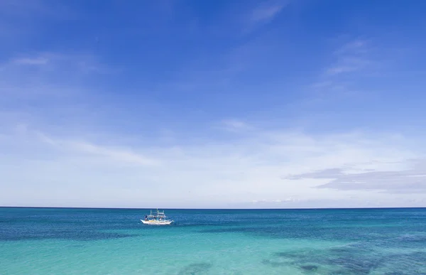 Trooppinen merimaisema sininen taivas ja valkoinen vene — kuvapankkivalokuva