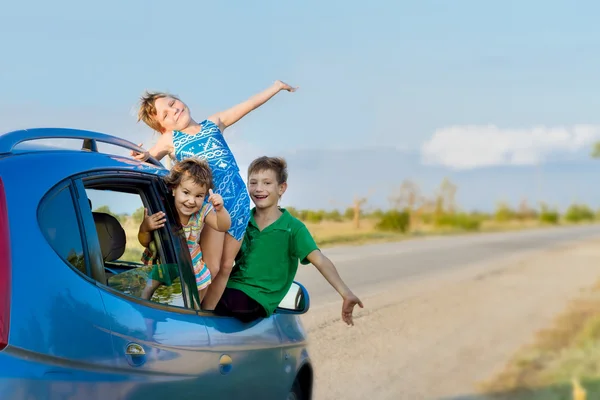 Троє щасливих дітей в машині, подорожі сім'єю, літні канікули Стокова Картинка