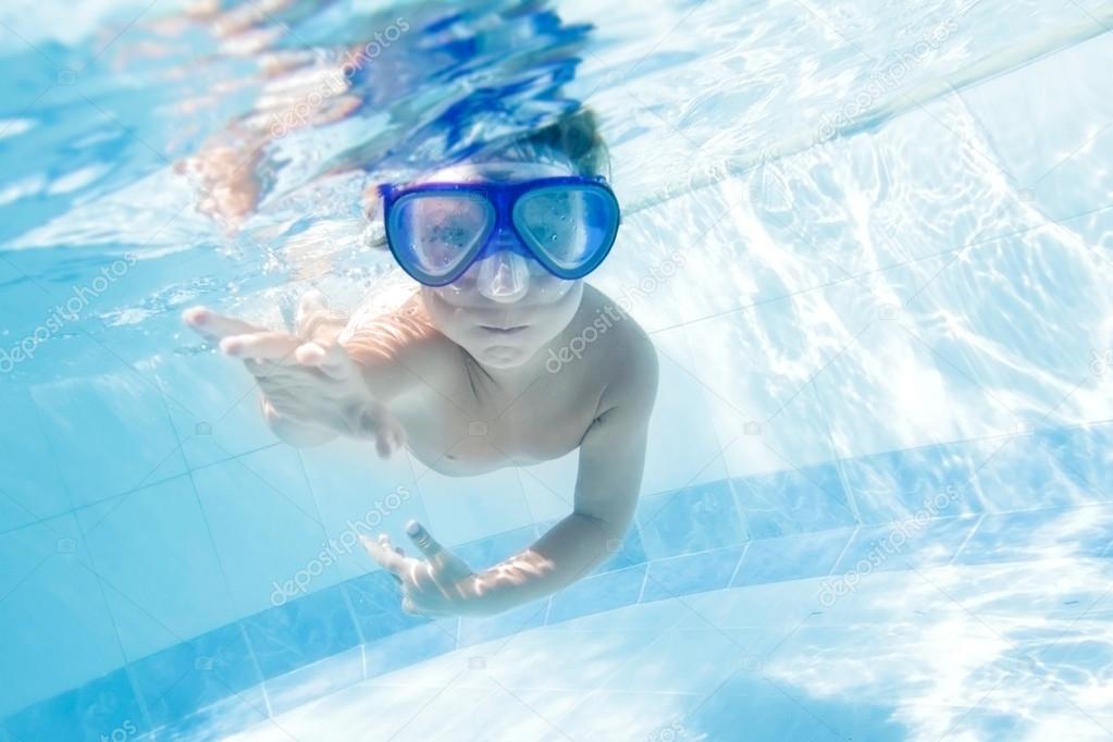 young child swimming underwater in pool