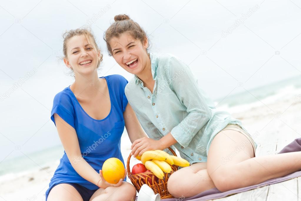 two young happy women enjoying life during outdoor picnic with f