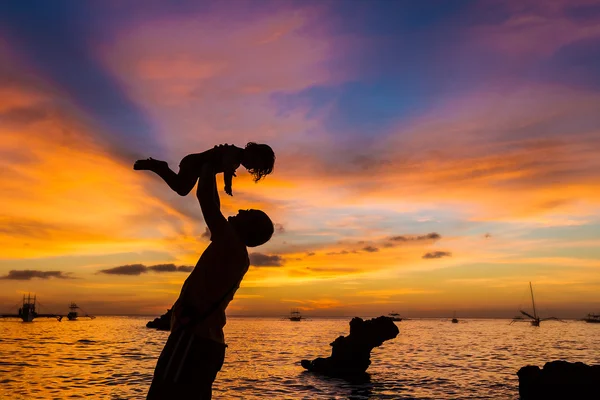 Siluety otce a dítěte na pozadí moře při západu slunce — Stock fotografie