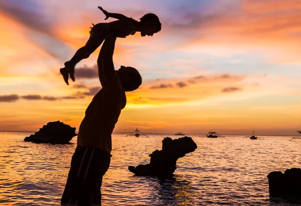 Силуэты отца и ребенка на фоне заката моря — стоковое фото