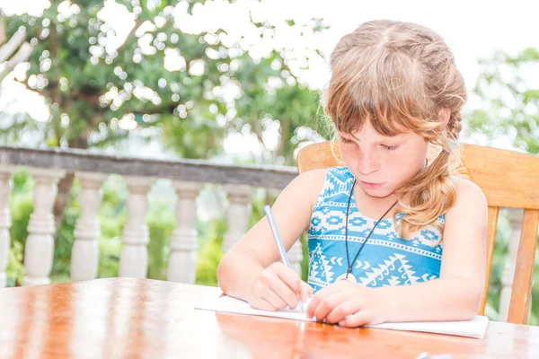 Bambina che scrive in quaderno, ritratto all'aperto, educati — Foto Stock