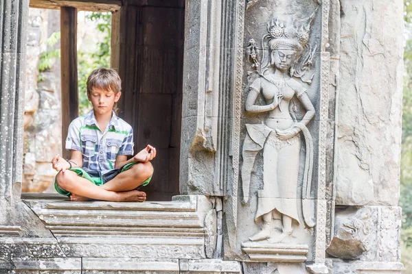 Молодой счастливый мальчик турист медитирует в Ангкор Ват, Камбоджа — стоковое фото