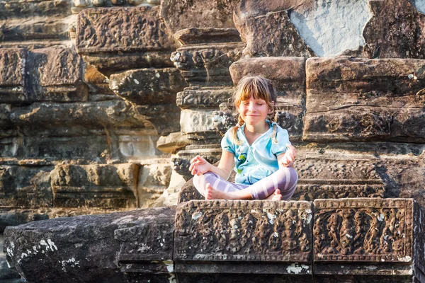 Young happy child girl tourist meditating in angkor wat, cambodi — Stock Photo, Image