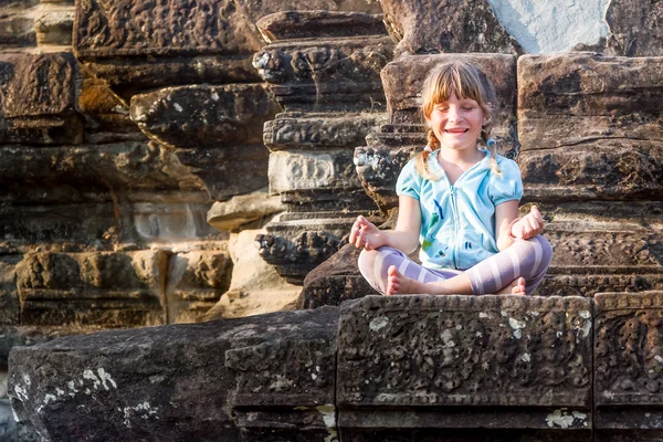 Young happy child girl tourist meditating in angkor wat, cambodi — Stock Photo, Image