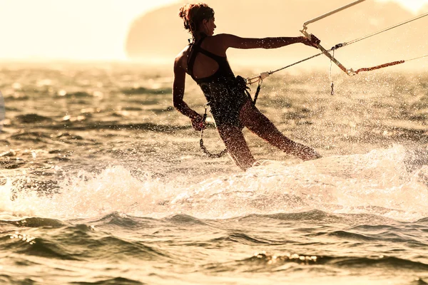 Mladá žena kite surfaře jede proti slunci — Stock fotografie