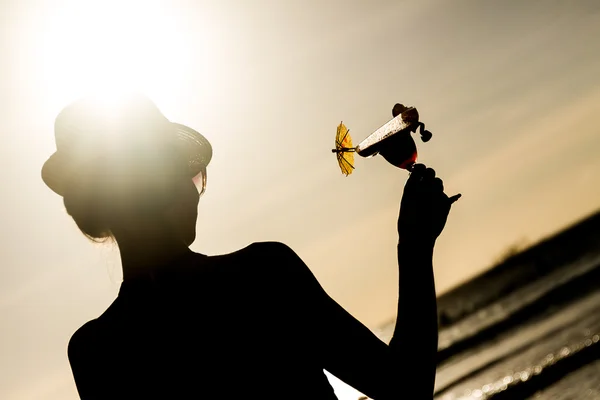 Sylwetka młoda kobieta z szkło tropikalny koktajl na słońce — Zdjęcie stockowe