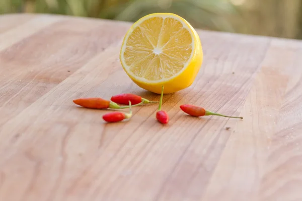 Lemon and chilli pepper on wooden cutting board, cooking backgro — Stock Photo, Image