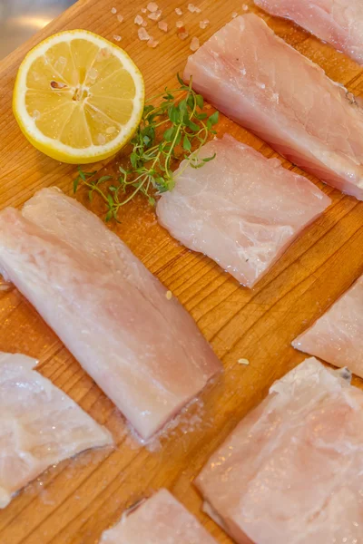 Fresh raw fish slices with lemon on wooden cutting board — Stock Photo, Image