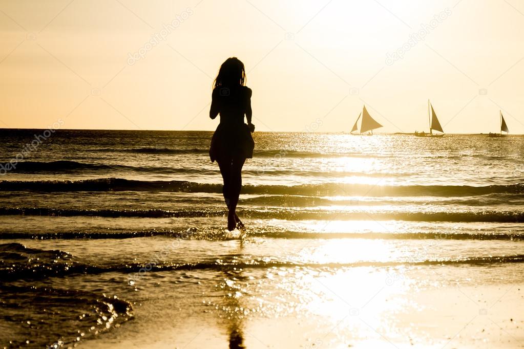 silhouette of young woman on sunset sea background