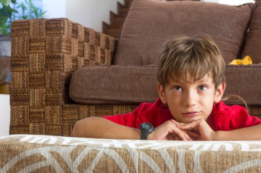 indoor portrait of young boy watching tv at home clipart