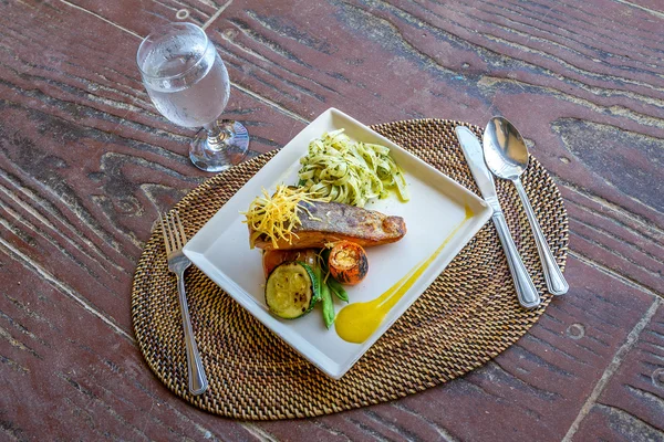 Grilled salmon steak served with pasta and vegetables in a small — Stock Photo, Image