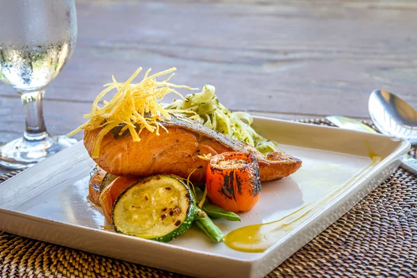 Grilled salmon steak served with pasta and vegetables in a small — Stock Photo, Image