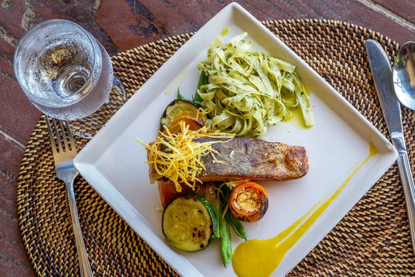 Grilled salmon steak served with pasta and vegetables in a small — Stock Photo, Image