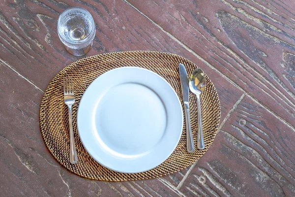 Порожня тарілка з ложкою, ножем і виделкою на дерев'яному натуральному фоні — стокове фото