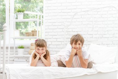 Beyaz yatakta evde oynayan iki küçük mutlu çocuklar