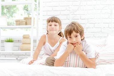 Beyaz yatakta evde oynayan iki küçük mutlu çocuklar