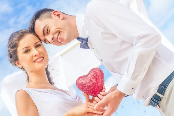 Bride and groom holding red heart as symbol of love, outdoor por — Stock Photo, Image