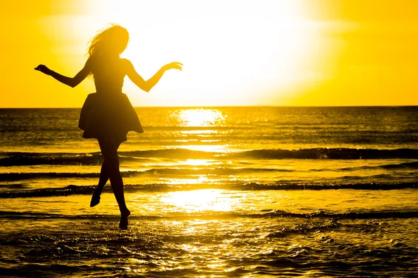 Sorglös kvinna dansar i solnedgången på stranden. semester vita — Stockfoto