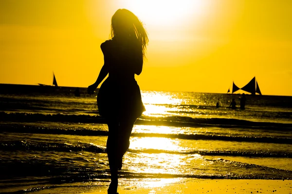 Sorglös kvinna dansar i solnedgången på stranden. semester vita — Stockfoto