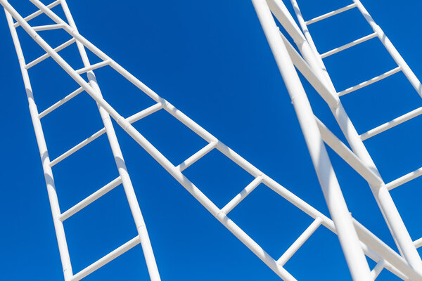 Maze of white ladders isolated over blue sky