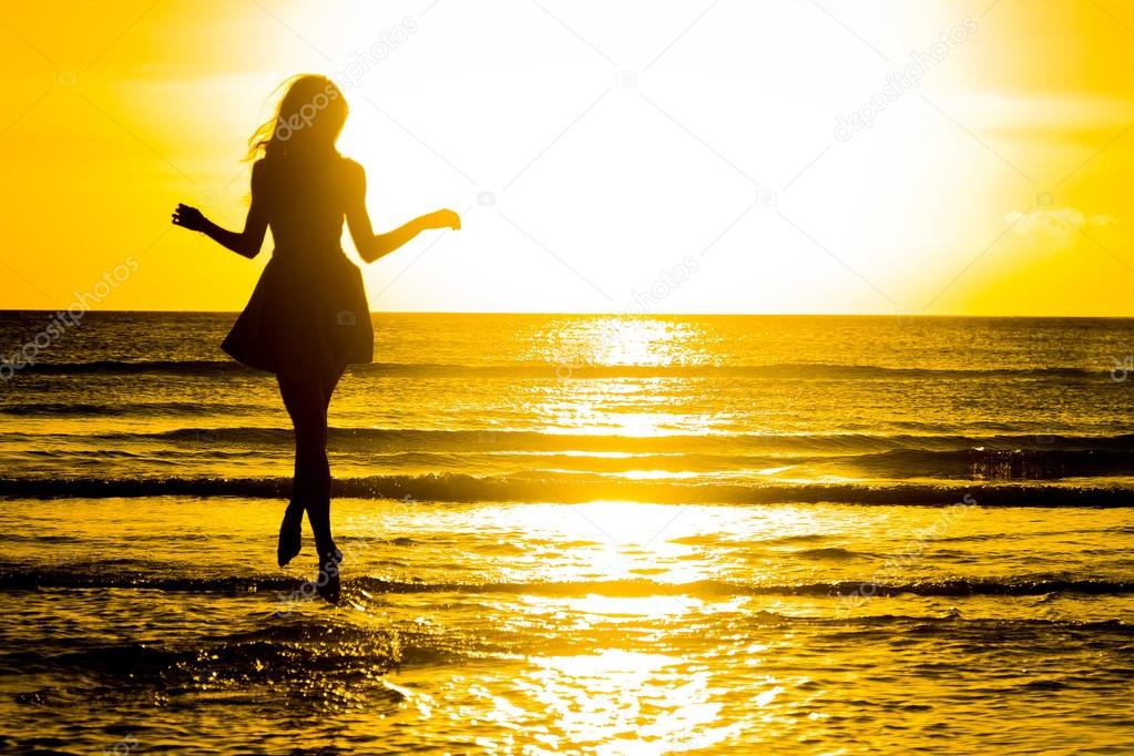 carefree woman dancing in the sunset on the beach. vacation vita