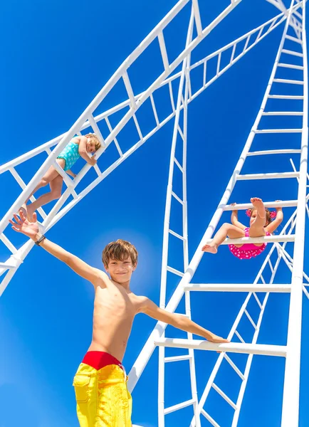 Young happy kids - boy and girl - climbing white ladders going n — Stock Photo, Image