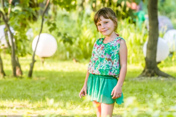 Söt liten flicka stående på naturliga blomma bakgrund — Stockfoto