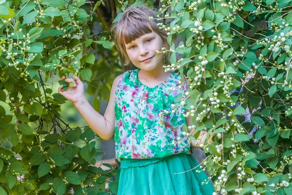 Söt liten flicka stående på naturliga blomma bakgrund — Stockfoto