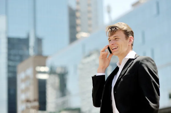 Geschäftsmann telefoniert auf Smartphone im Hintergrund Bürogebäude — Stockfoto