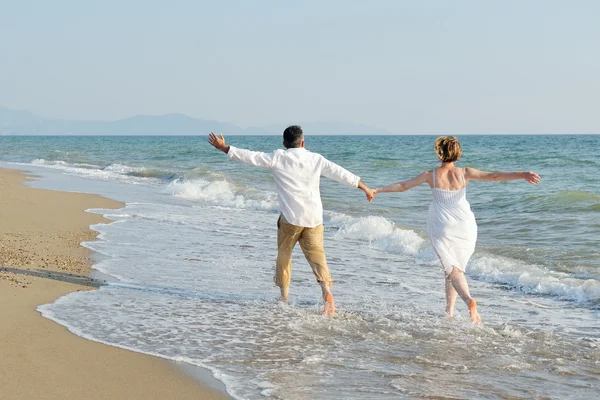 Feliz pareja corriendo en la playa — Foto de Stock