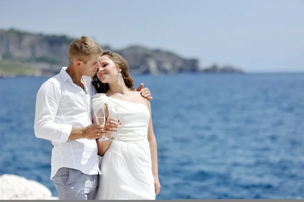 Jeune couple marié toast par la mer après leur mariage — Photo