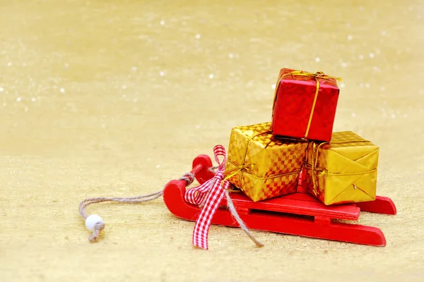 Рождественские сани и подарочные коробки украшения на золотом фоне — стоковое фото