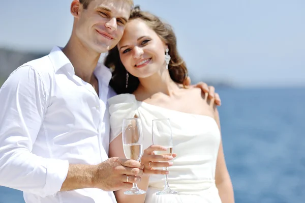 Mariée et marié portant un toast au bord de la mer le jour du mariage — Photo