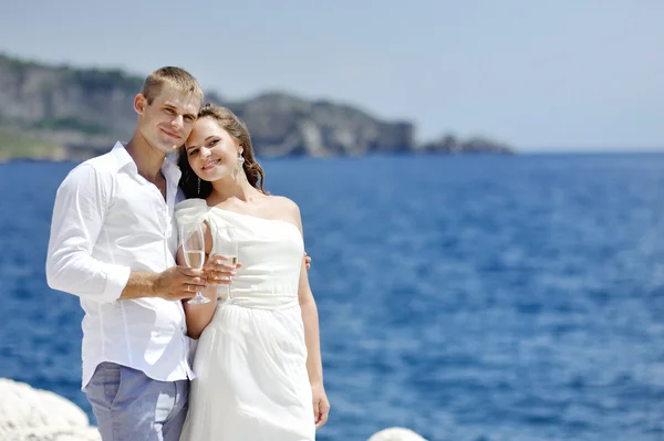 Novia y novio haciendo un brindis junto al mar en el día de la boda —  Fotos de Stock