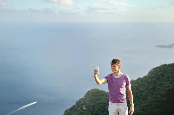 Young man taking selfie on top of a mountain over sea — Stock Photo, Image