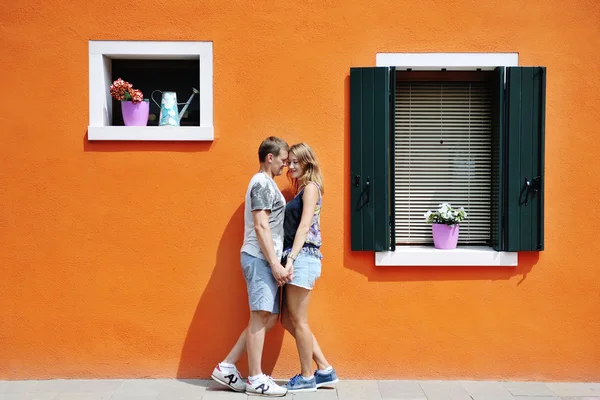 Šťastný pár, drželi se za ruce oranžové barevné zdi v Burano, Benátky, Itálie — Stock fotografie