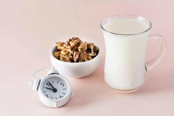 Good sleep. Foods for good sleep - milk, walnuts and alarm clock on pink background