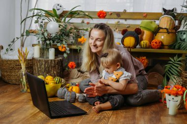 COVID zamanındaki tatiller. Mutlu aile, anne ve bebek Cadılar Bayramı 'nı internet üzerinden yeni normal salgın zamanda kutluyorlar. Çevrimiçi Tatil Partisi konsepti