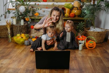 COVID zamanındaki tatiller. Mutlu aile, anne ve bebek Cadılar Bayramı 'nı internet üzerinden yeni normal salgın zamanda kutluyorlar. Çevrimiçi Tatil Partisi konsepti