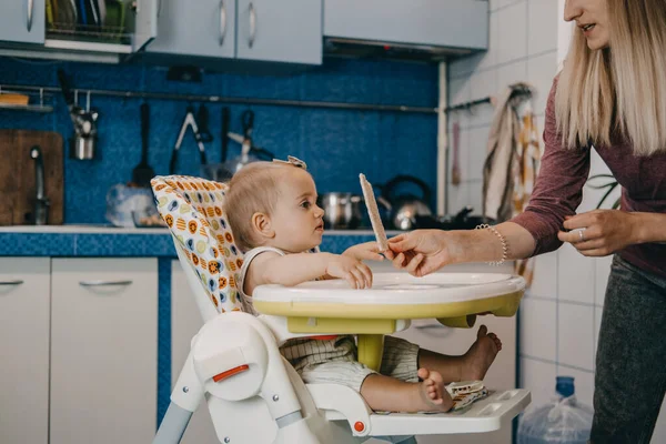 Alimentación del bebé. Los mejores alimentos para los dedos para bebés pequeños. Niña pequeña con pan crujiente, galletas de cereales sentadas en la silla de alimentación — Foto de Stock