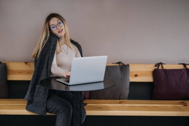 Fazladan para kazanmak, ek iş yapmak, para kazanmak, hobileri paraya çevirmek, iş ekonomisi, dijital göçebe. Genç bir kadın, laptopu ve akıllı telefonu olan bir öğrenci dışarıda çalışıyor.