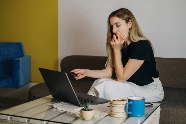 Compra de impulso, compras en línea, moda rápida, adicto a las compras, el gasto de concepto de dinero. Mujer joven en casa con tarjeta de crédito y el uso de ordenador portátil y teléfono celular — Foto de Stock