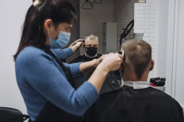 Peluquerías, peluquerías cerradas, segundo cierre. Peluquería en mascarilla peeling y peinado cliente masculino en peluquería. Peluquería y el hombre cliente están usando máscaras faciales protectoras. —  Fotos de Stock